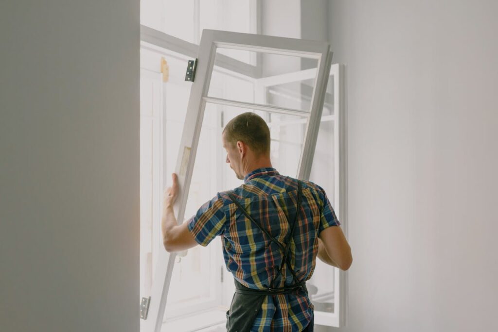A professional installer fitting a modern window in a well-lit home interior.